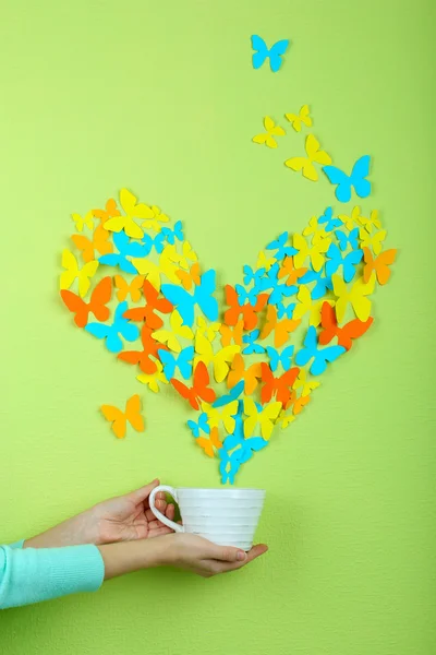 Paper butterflies fly out of cup on green wall background — Stock Photo, Image