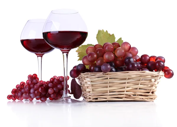 Weingläser mit Rotwein und Trauben im Weidenkorb isoliert auf weiß — Stockfoto