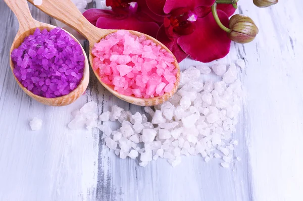 Bodegón con hermosa flor de orquídea y cucharas de madera con sal marina, sobre fondo de madera de color — Foto de Stock