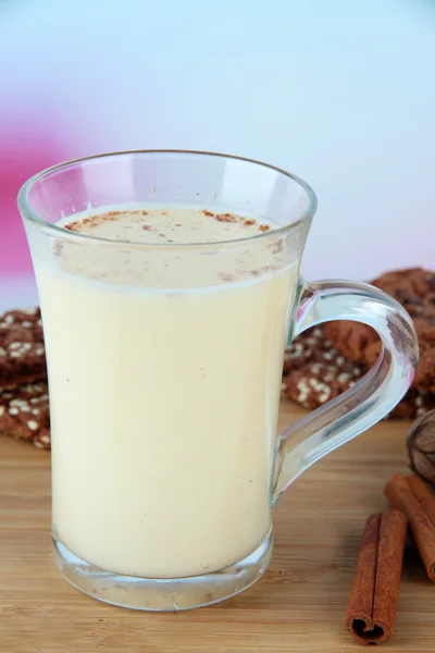 Pohár vaječný likér se skořicí a soubory cookie v tabulce na světlé pozadí — Stock fotografie