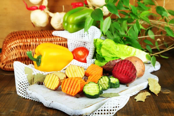 Mooie gesneden groenten, op houten bord, op houten achtergrond — Stockfoto