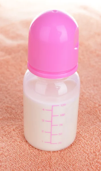 Bottiglia bambino con latte su sfondo asciugamano — Foto Stock