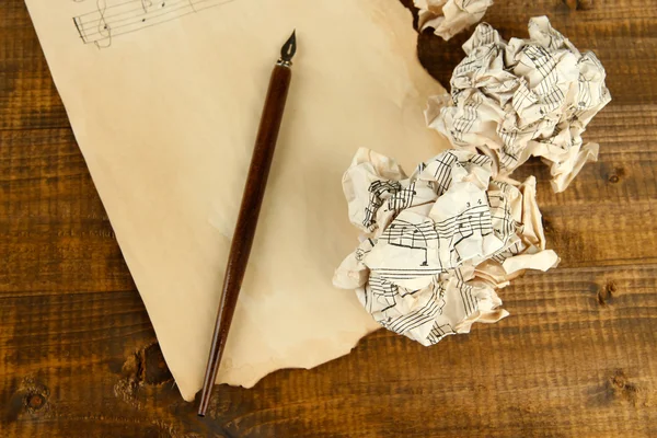 Pelotas de papel arrugadas con lápiz de tinta y hoja de música sobre fondo de madera —  Fotos de Stock