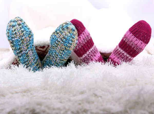 Beine in bunten Socken auf weißem Teppich Hintergrund — Stockfoto