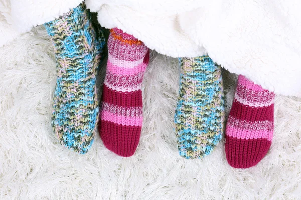 Beine in bunten Socken auf weißem Teppich Hintergrund — Stockfoto