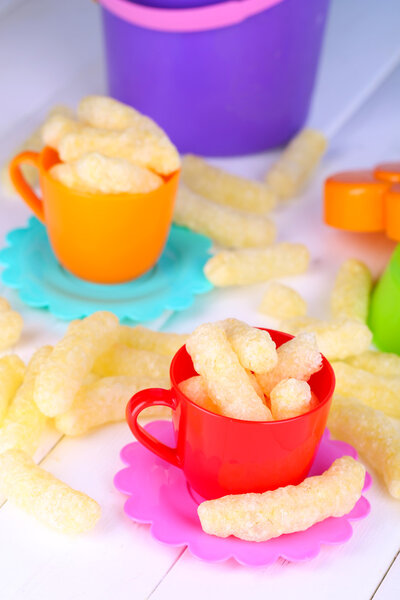 Corn sticks in children toy dishes on wooden table close-up