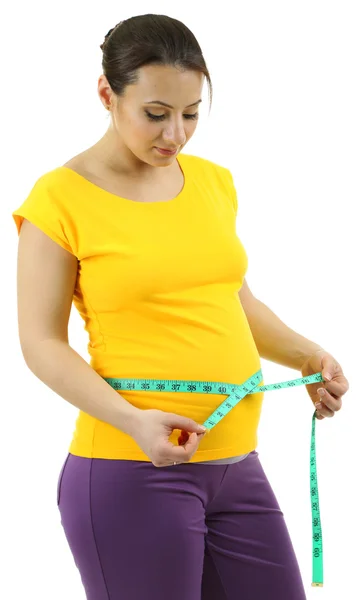 Молодая беременная женщина измеряет ее живот изолирован на белом — стоковое фото