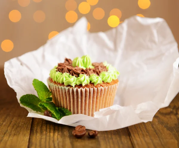 Tasty cupcake with butter cream, on wooden table, on lights background — Stock Photo, Image