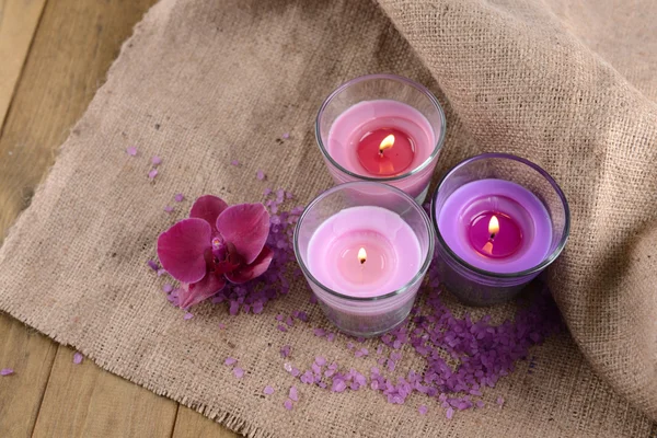 Složení s krásné barevné svíčky, mořská sůl a květy orchidejí, na dřevěné pozadí — Stock fotografie