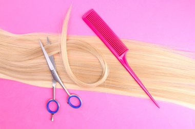 uzun sarı saçları tarak ve pembe bir arka plan için makaslar