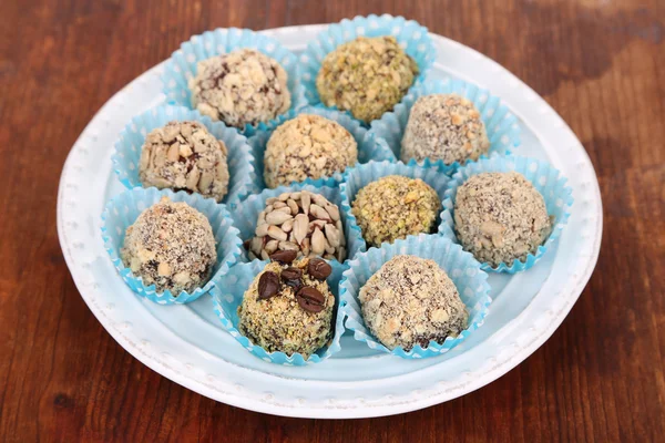 Set van chocolade snoepjes, op plaat, op houten achtergrond — Stockfoto