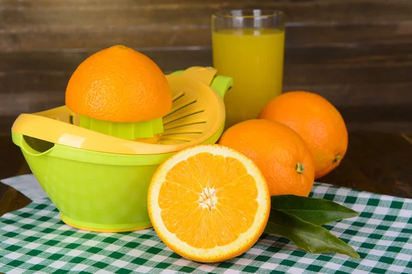 Citrus press and oranges on table on wooden background — Stock Photo, Image