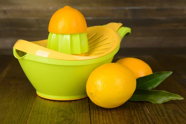 Citrus press and lemons on table on wooden background — Stock Photo, Image