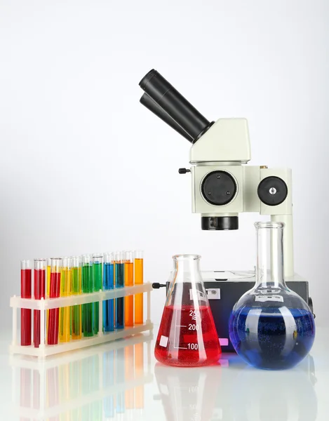 Test tubes with colorful liquids and microscope isolated on white — Stock Photo, Image