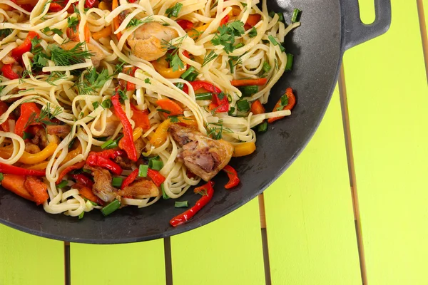 Macarrão com legumes em wok no fundo de madeira — Fotografia de Stock