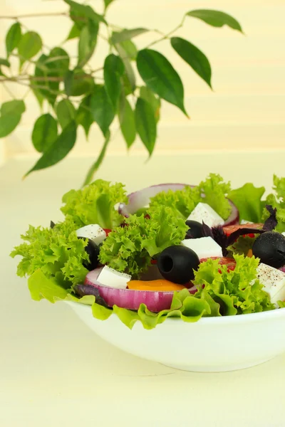 Grekisk sallad på tallriken på bordet på ljus bakgrund — Stockfoto