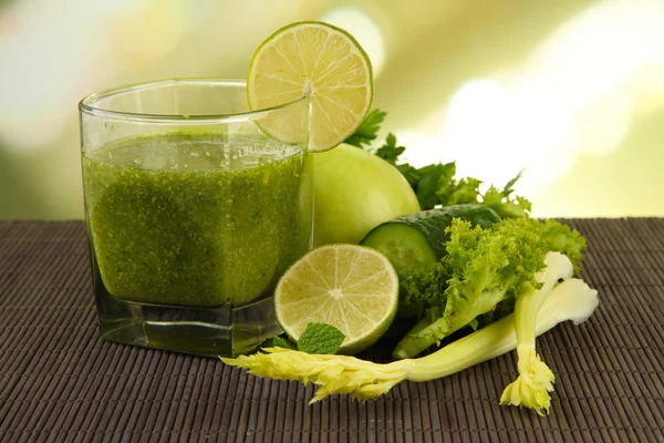 Bicchiere di succo di verdura verde e verdure su tappetino di bambù su sfondo luminoso — Foto Stock