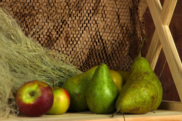 Reife Äpfel und Birnen im Regal auf braunem Hintergrund — Stockfoto