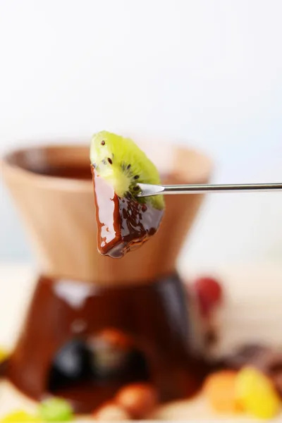 Chocolade fondue met fruit, op houten tafel, op lichte achtergrond — Stockfoto