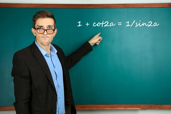 Young teacher near chalkboard in school classroom — Stock Photo, Image