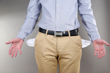 adam boş ceplerini gri arka plan üzerinde gösterilen