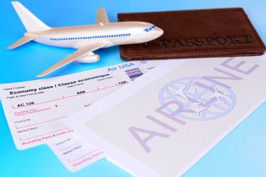 Açık mavi arka planda pasaportlu uçak biletleri.