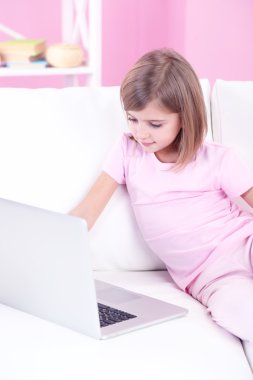 oturma odasındaki kanepe üstünde laptop ile küçük kız