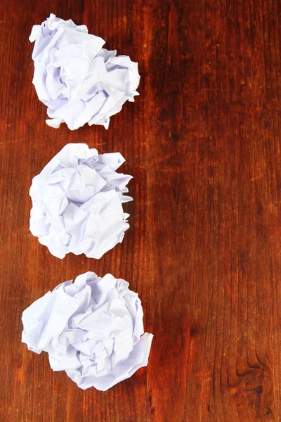 Bolas de papel enrugadas no fundo de madeira — Fotografia de Stock