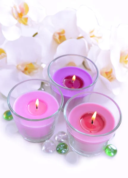 Lindas velas coloridas e flores de orquídeas, isoladas em branco — Fotografia de Stock