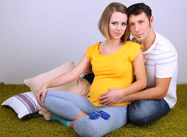 年轻孕妇和她的丈夫坐在家里的地板上 — 图库照片