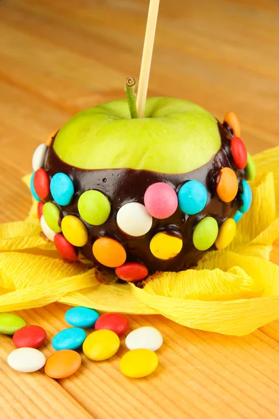 Candied apple on stick on wooden table — Stock Photo, Image