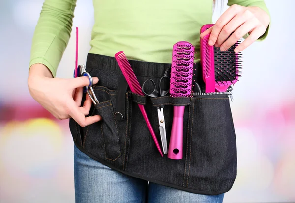 Woman hairdresser with tool belt on bright background — Stock Photo, Image