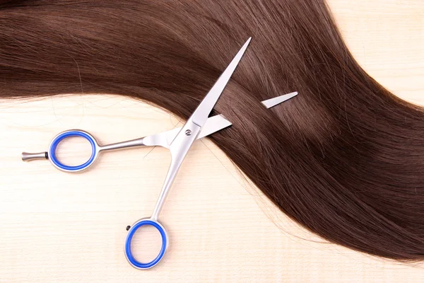 Long brown hair and scissors on wooden background — Stock Photo, Image