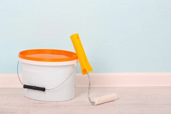 Paint and roll on floor in room on wall background — Stock Photo, Image