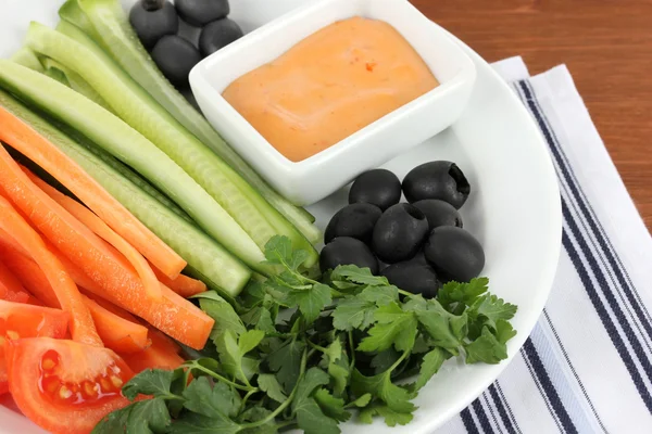 Diverse råa grönsaker pinnar i plattan på träbord närbild — Stockfoto