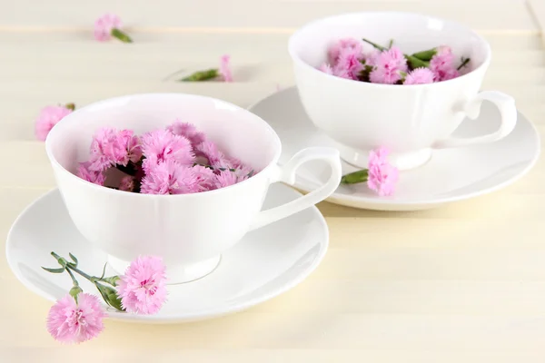 Many small pink cloves in cups on wooden background — Stock Photo, Image