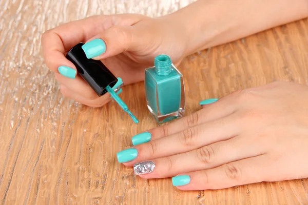 Mooie vrouw handen met blauwe manicure, op een achtergrond met kleur — Stockfoto