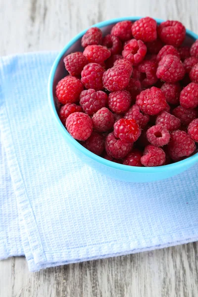 Reife süße Himbeeren in Schale auf Holzgrund — Stockfoto