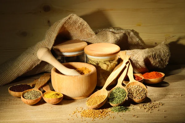 Assortimento di spezie in cucchiai e vasetti di legno, su fondo di legno — Foto Stock