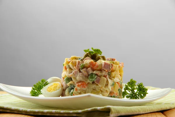 Salada tradicional russa Olivier, em guardanapo de cor, em mesa de madeira, em fundo cinza — Fotografia de Stock