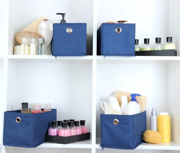 Blue textile boxes with cosmetic products for personal care in white shelves