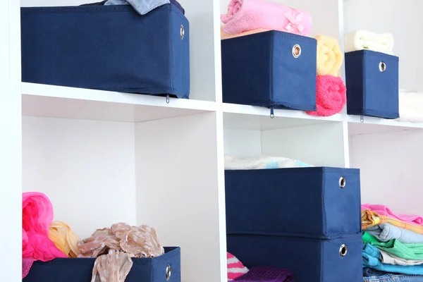 Синие текстильные коробки с игрушками и одеждой на белых полках — стоковое фото