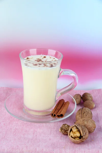 Tasse Eierlikör mit Zimt und Nüssen auf Tisch auf hellem Hintergrund — Stockfoto