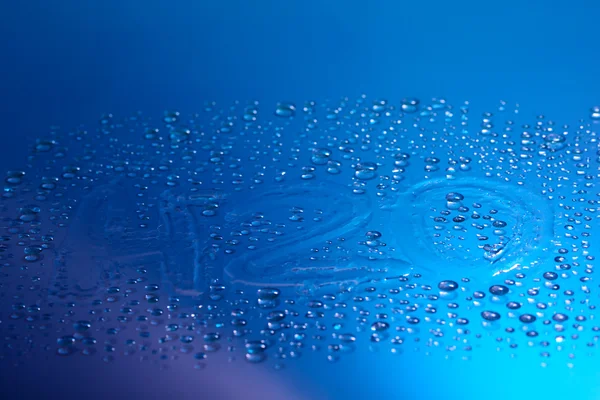H2O geschreven op waterdruppels op blauwe achtergrond — Stockfoto