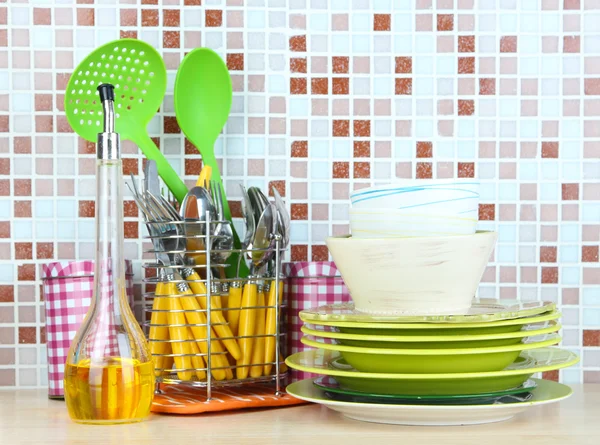 Platos y cubiertos en la cocina en la mesa en el fondo de azulejos de mosaico —  Fotos de Stock