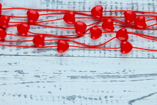 Heart-shaped beads on string on wooden background — Stock Photo, Image