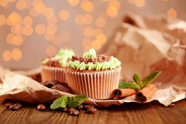 Leckere Cupcakes mit Buttercreme, auf Holztisch, auf Lichtern Hintergrund — Stockfoto