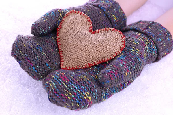 Female hands in mittens with heart on snow background — Stock Photo, Image