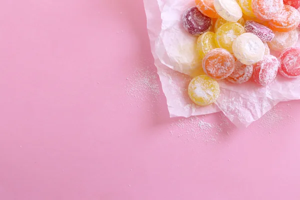 Süße mehrfarbige Bonbons auf Papier, auf farbigem Hintergrund — Stockfoto