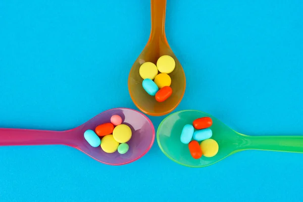 Πλαστικά κουτάλια με χρώμα χάπια σε μπλε φόντο — Φωτογραφία Αρχείου